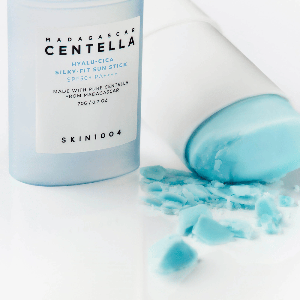 En solkremstift med SPF50+ ligger åpen ved siden av lokket, innholdet delvis smurt ut på en hvit overflate. Teksten på emballasjen nevner ingredienser fra Madagaskar.