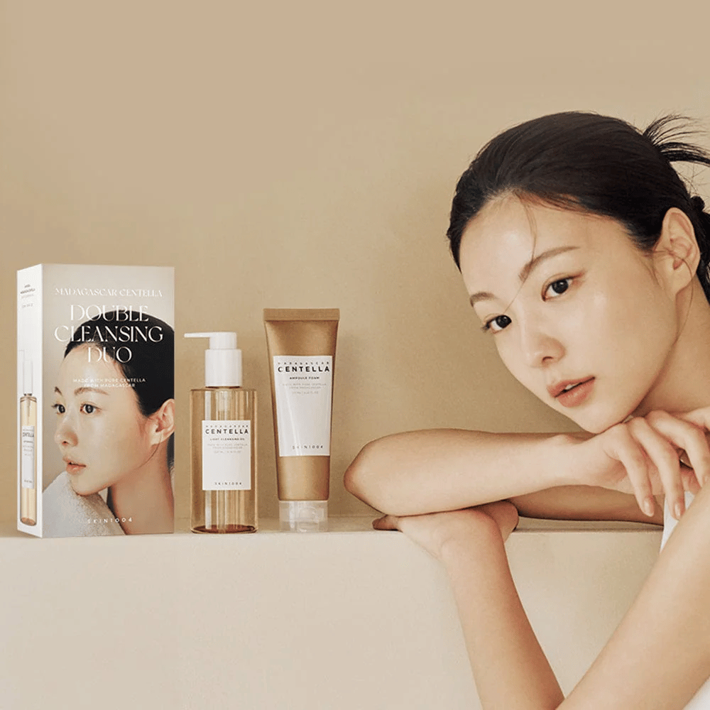 SKIN1004 Madagascar Centella Double Cleansing Duo Set med kartong, oljebasert rens, skumrens og modell med fuktet hud mot beige bakgrunn.