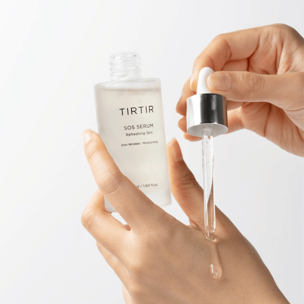 Hender som drypper TIRTIR SOS Serum fra en pipette, beregnet for hudpleie.