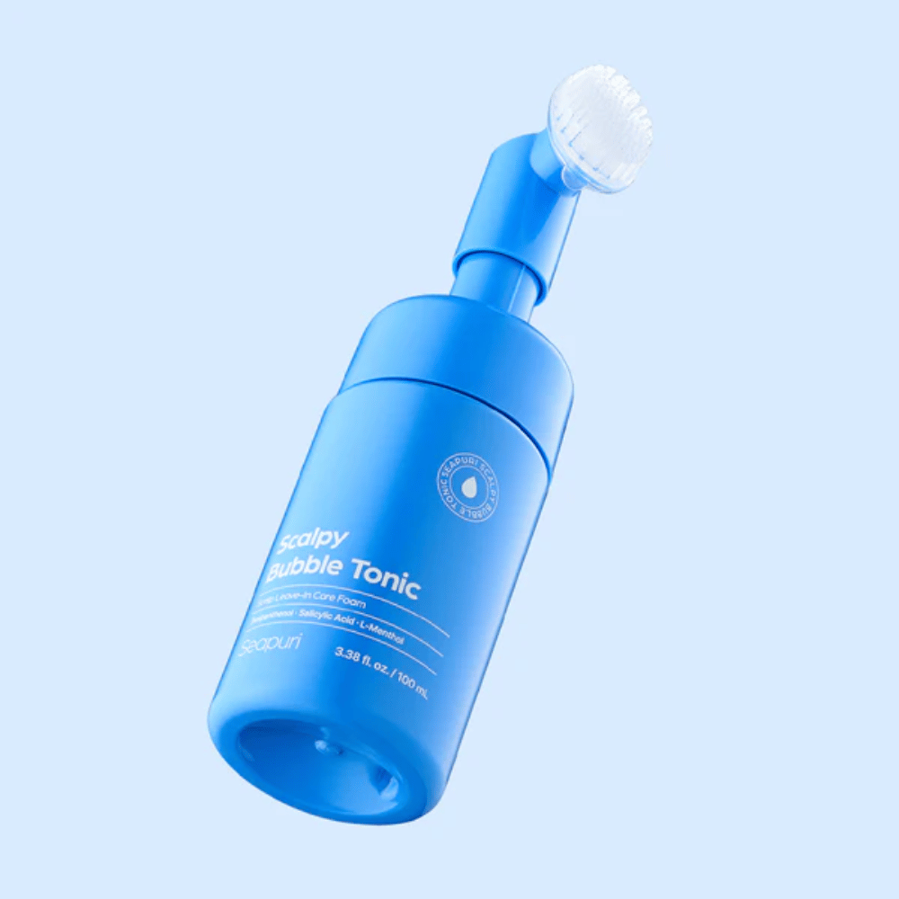 Stilrent produktbilde av Seapuri Scalpy Bubble Tonic mot lys blå bakgrunn som fremhever det moderne designet og den unike børstetoppen for hodebunnspleie.