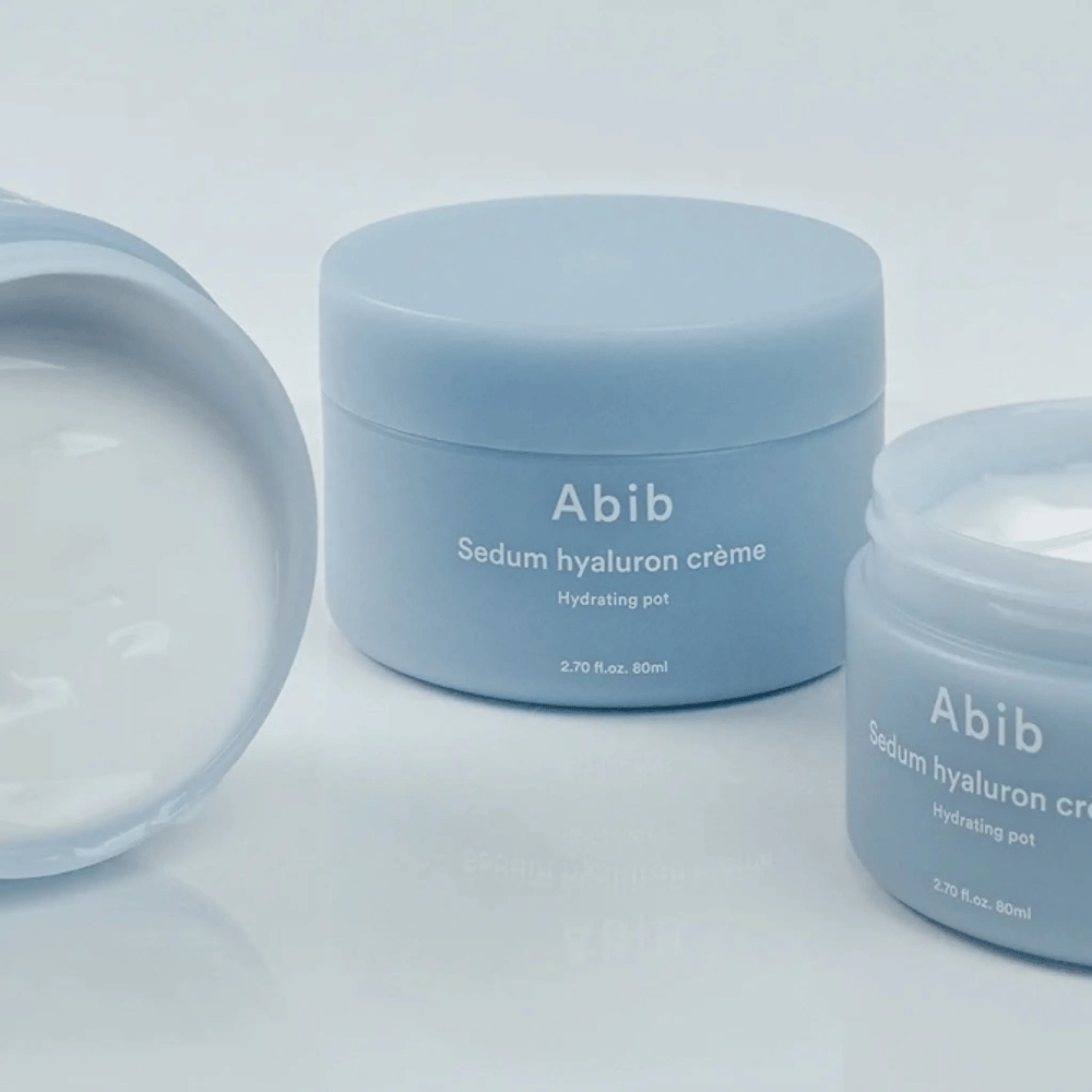 Tre bokser av Abib Sedum Hyaluron Crème Hydrating Pot 80 ml i lyseblå minimalistisk design, hvorav en åpen boks viser den kremete hvite konsistensen.