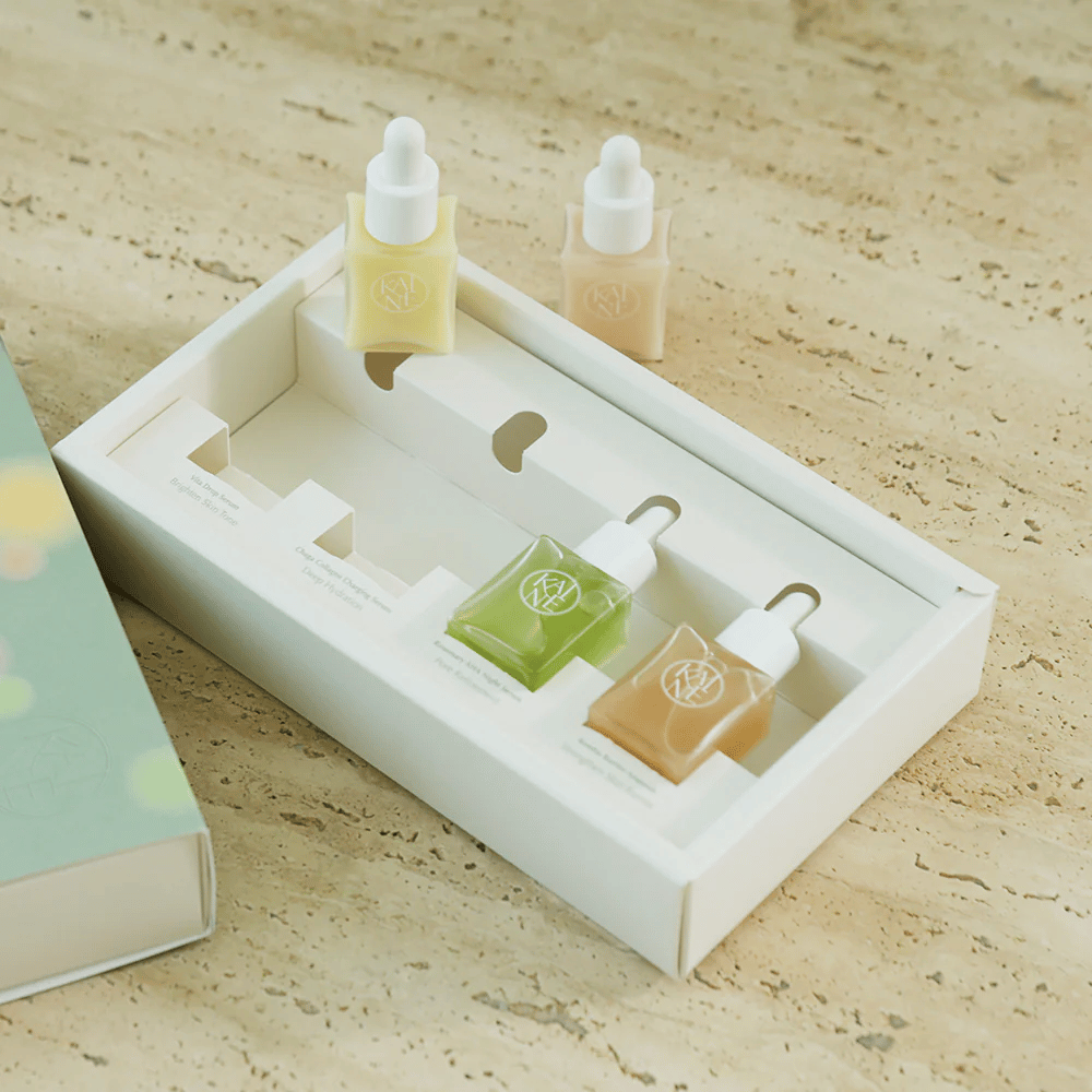 Fire fargerike serumflasker fra KAINE Serum Discovery Kit med pipettekork, designet for å møte ulike hudbehov i en minimalistisk og stilren emballasje.