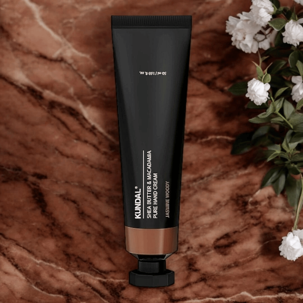KUNDAL Shea Butter & Macadamia Pure Hand Cream Jasmine Woody plassert på marmor med blomster – nærende håndkrem som pleier tørre hender og gir en elegant jasmine woody-duft.