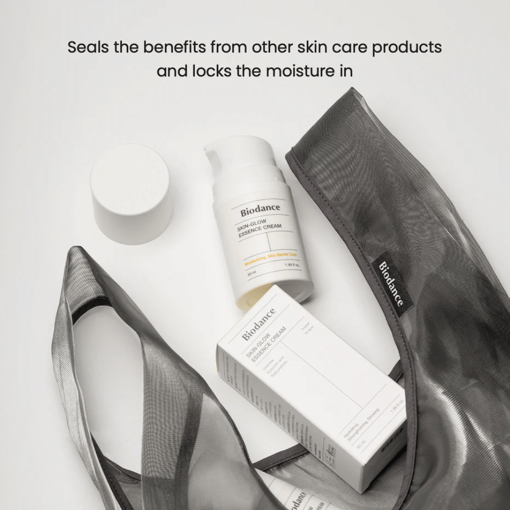 Biodance Skin-Glow Essence Cream stående i fokus sammen med produkteboks og en svart gjennomsiktig toalettmappe, med tekst ovenfor som understreker kremens evne til å kapsle inn fuktighet og forsterke effekten av andre hudpleieprodukter.