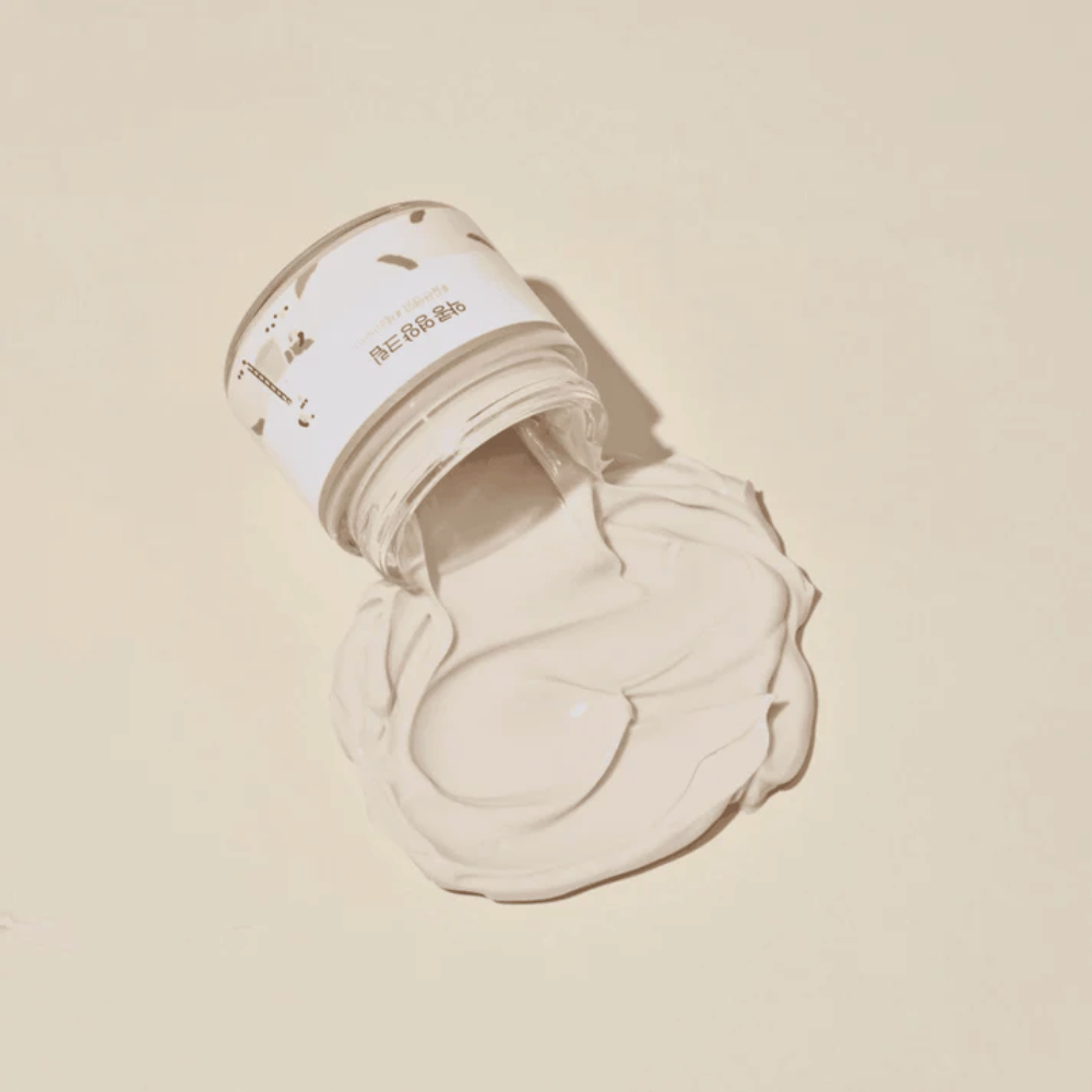 Mixsoon Soybean Nourishing Cream sølt ut av krukken på en beige bakgrunn. Kremens fyldige konsistens viser dens intensive fuktighetsgivende egenskaper.