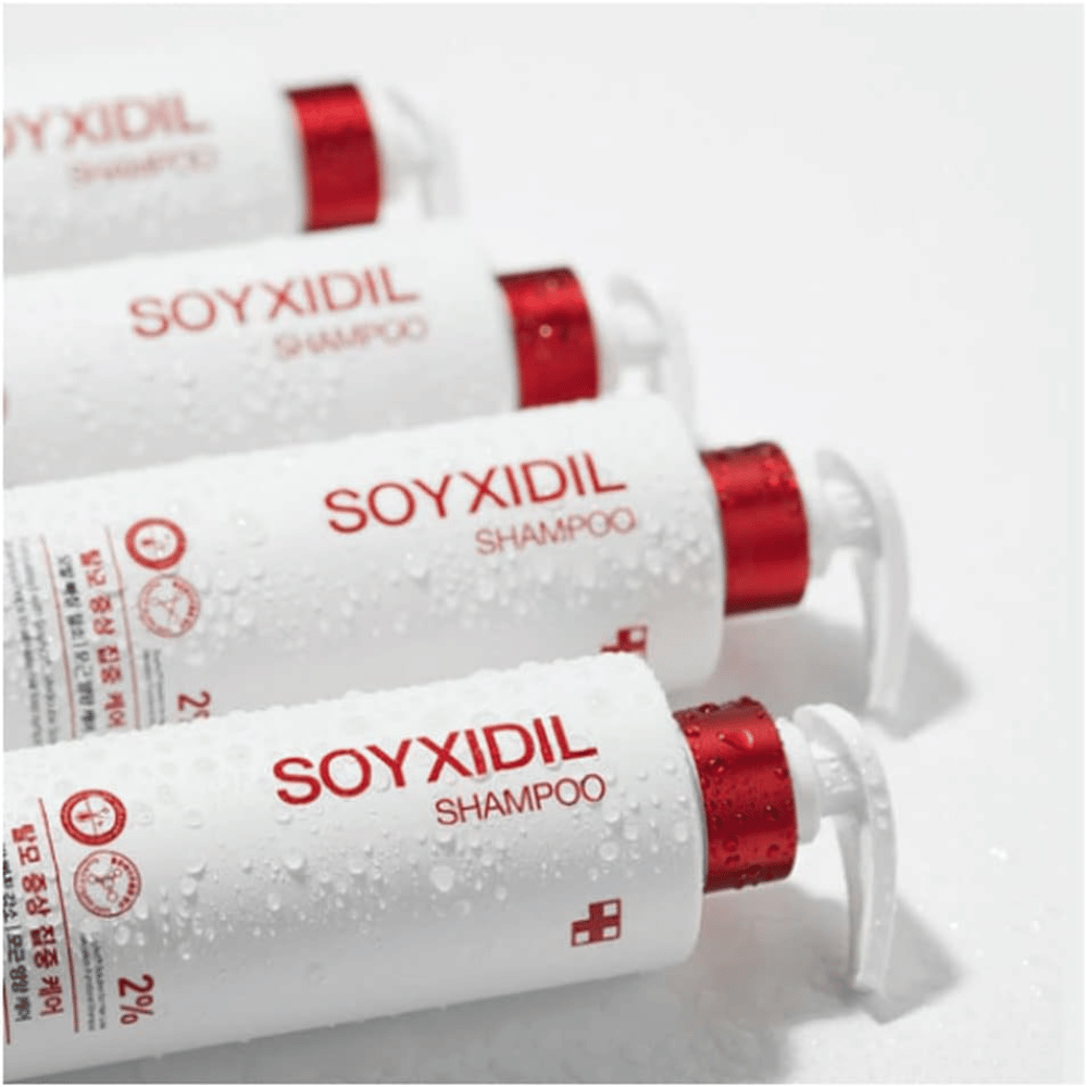 Flere flasker av Medicube Soyxidil Shampoo ligger på rad med vanndråper – viser produktets friske og pleiende følelse.