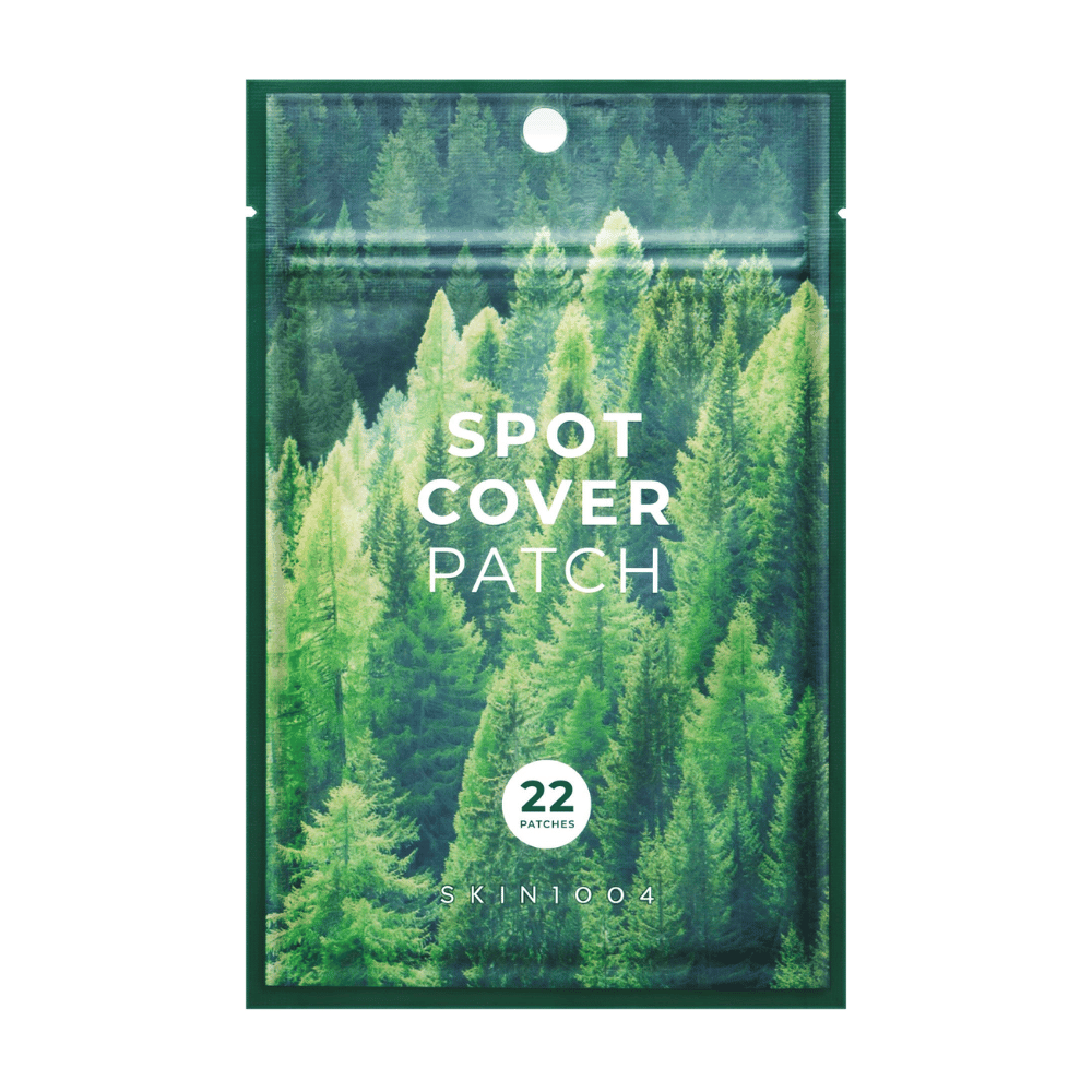 Forpakning med "Spot Cover Patch" som inneholder 22 plaster, designet med et grønt skogsmotiv. Teksten "SPOT COVER PATCH" er trykt i hvitt på forsiden, og en sirkel markerer antall plaster. Produktet er fra merket SKIN1004.