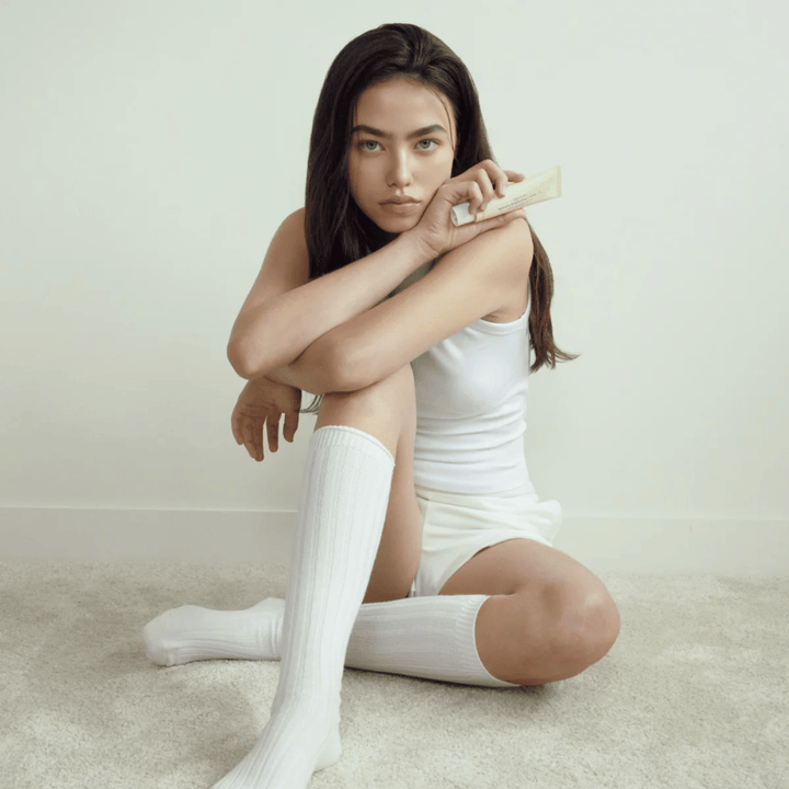 Livsstilsbilde med modell som holder produktet i et lyst og minimalistisk miljø. Bildet formidler en ren, naturlig og rolig hudpleiefølelse knyttet til glow og brightening-effekt.