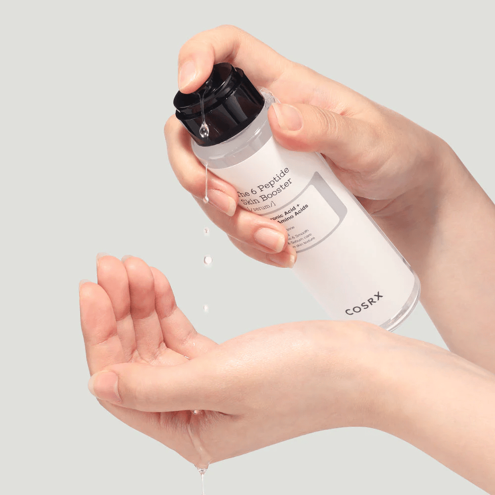 Hender som heller ut hudpleieprodukt fra en gjennomsiktig flaske med teksten "The Peptide Skin Booster".
