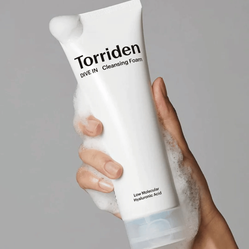 En hånd som holder et pH-balansert rør Torriden DIVE-IN Low Molecular Hyaluronic Acid Cleansing Foam 150ml.