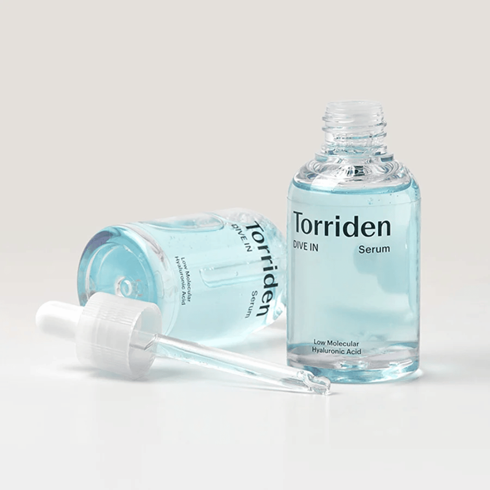 En flaske Torridens DIVE-IN Low Molecule Hyaluronic Acid Serum 50ml ved siden av en flaske vann, som fremhever hyaluronsyreserum og fuktighet.
