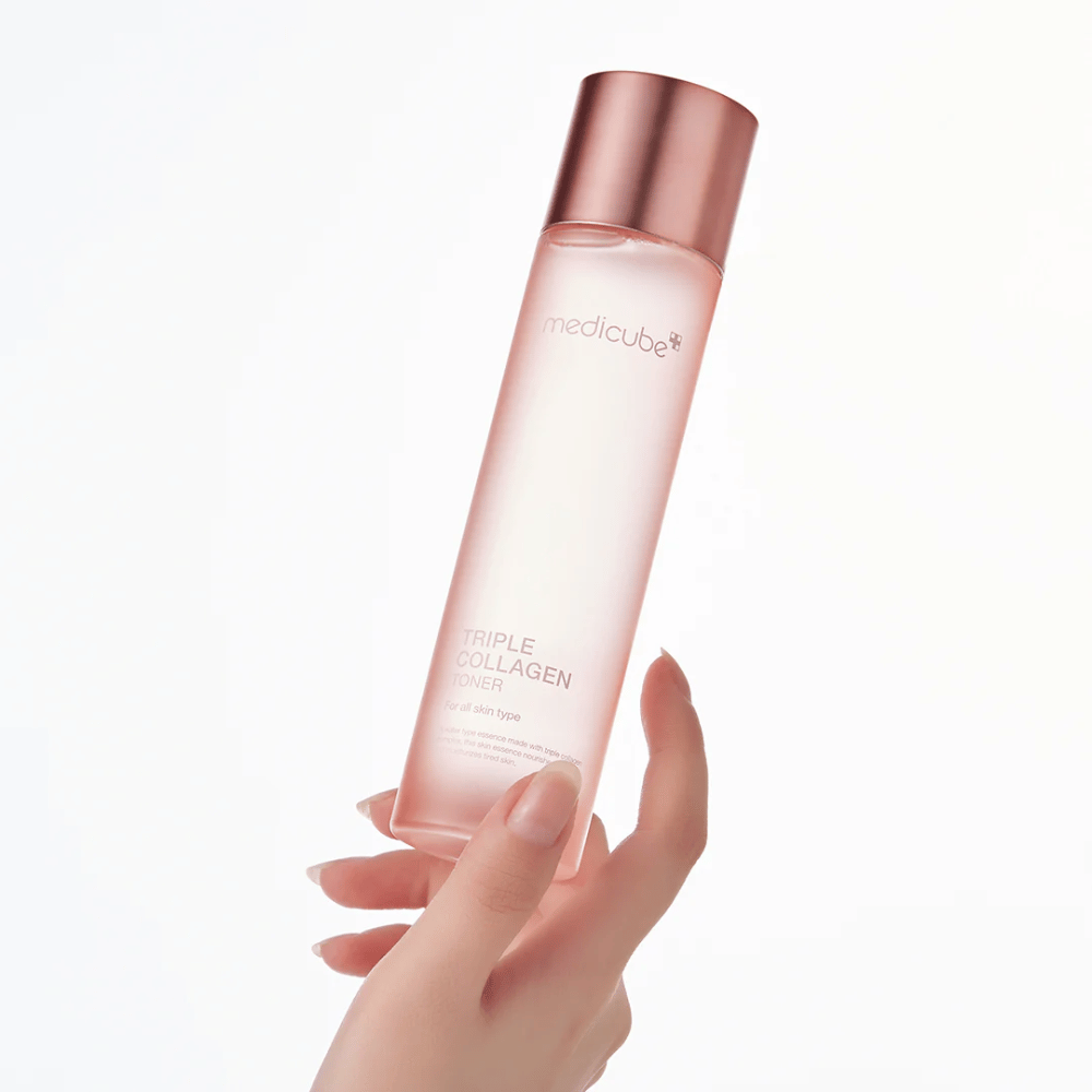 Hånd som holder i en rosa flaske av Medicube Triple Collagen Toner 4.0, en fuktighetsgivende og oppstrammende toner for alle hudtyper.