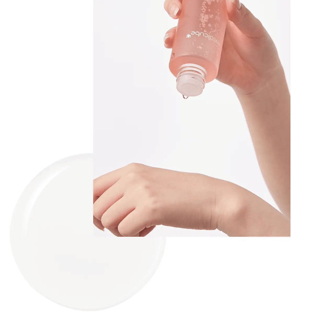 Hånd som heller ut Medicube Triple Collagen Toner 4.0 fra en rosa flaske på huden, viser den fuktighetsgivende konsistensen.