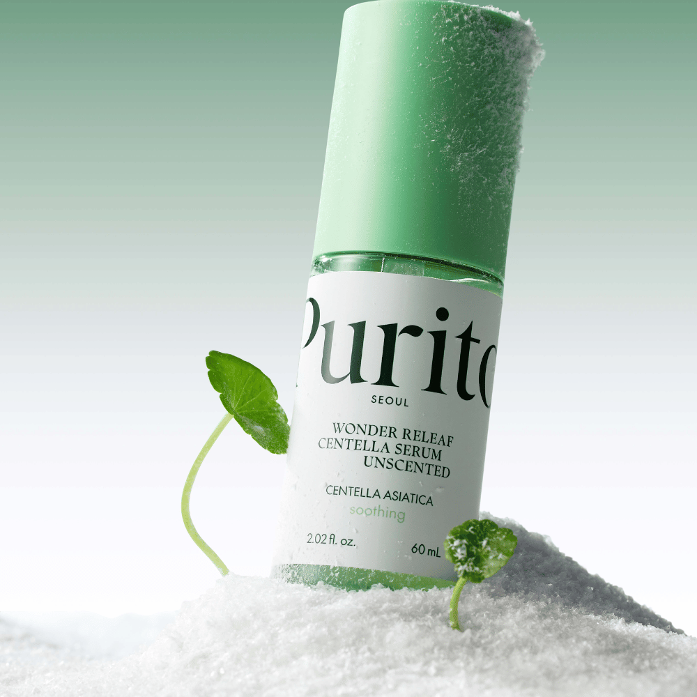 Flaske med Purito Centella Serum ligger i snø, grønne blader vises, mot en myk grønn bakgrunn.