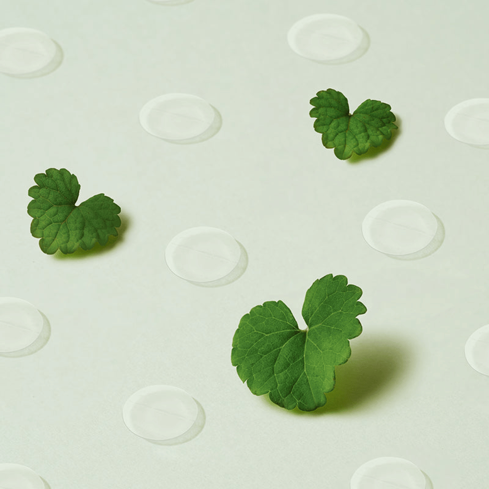 Gjennomsiktige spot patches sammen med centella-blader som illustrerer Purito Wonder Releaf Centella Spot Patch og dens beroligende effekt på betent og sensitiv hud.