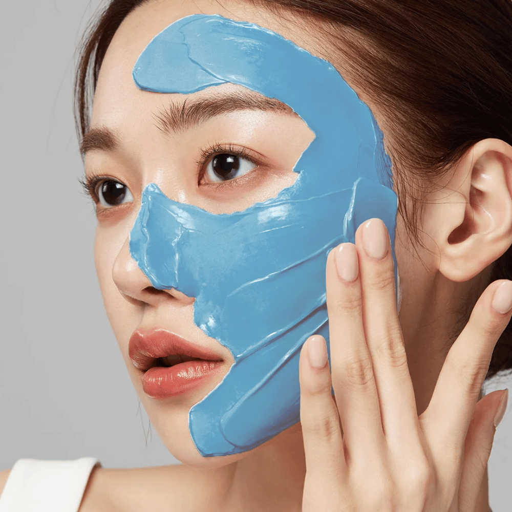 Modell med blå ansiktsmaske fra Medicube, dekker T-sonen for porepleie.