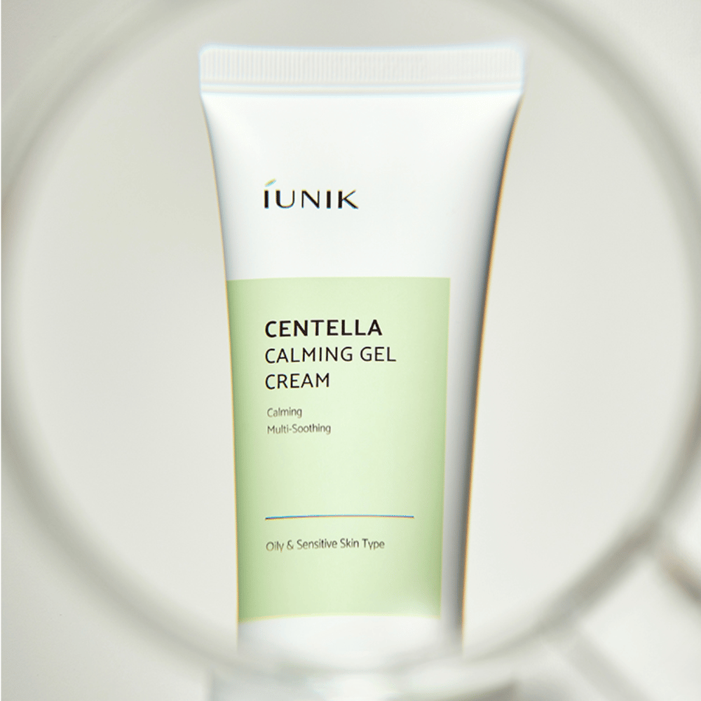 En tube iUNIK Centella Calming Gel Cream med hvit og lysegrønn design står oppreist, sett gjennom en rund forstørrelsesglasslignende ramme.