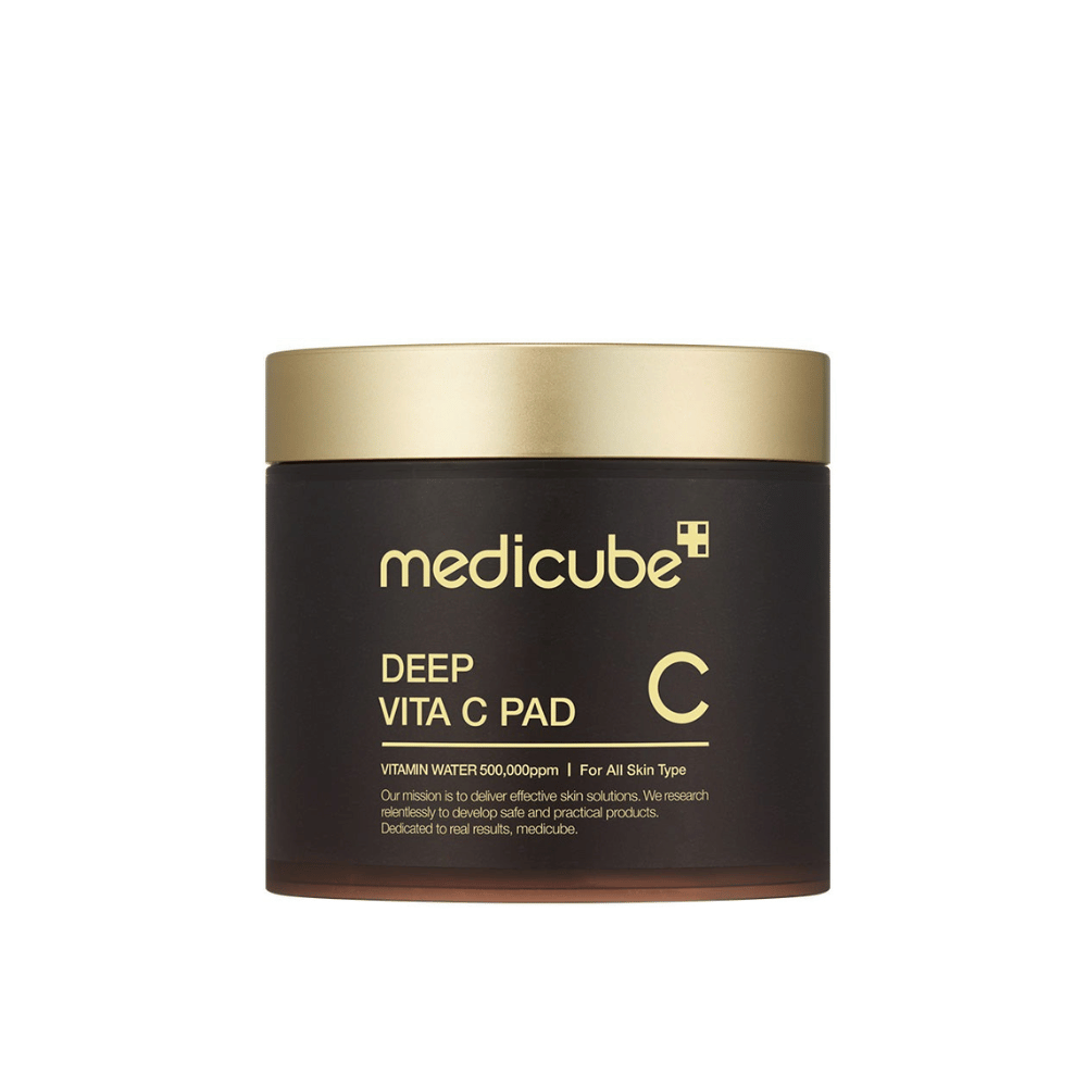 En boks fra medicube, merket "Deep Vita C Pad", med gullokk og mørk kropp. Tekst på boksen angir C-vitamin og egnethet for alle hudtyper. Bakgrunnen er nøytral.