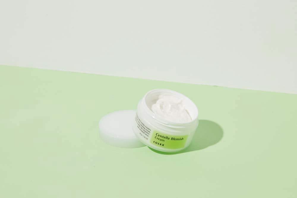 En krukke COSRX Centella Blemish Cream 30ml som står på en grønn overflate.