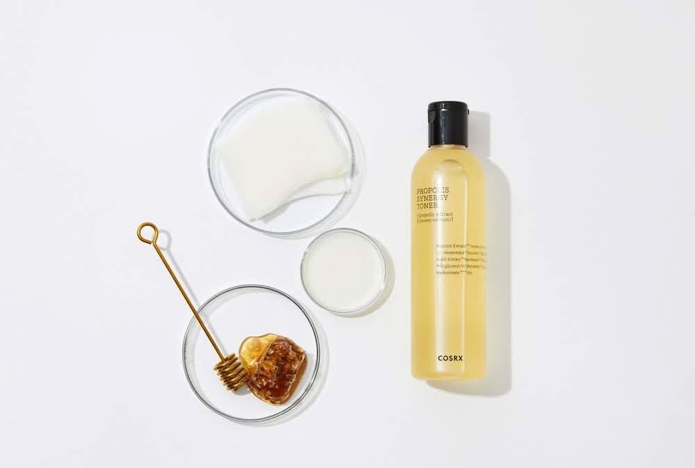 En flaske COSRX Full Fit Propolis Synergy Toner 150ml med betennelsesdempende og antibakterielle effekter, plassert på en hvit overflate.