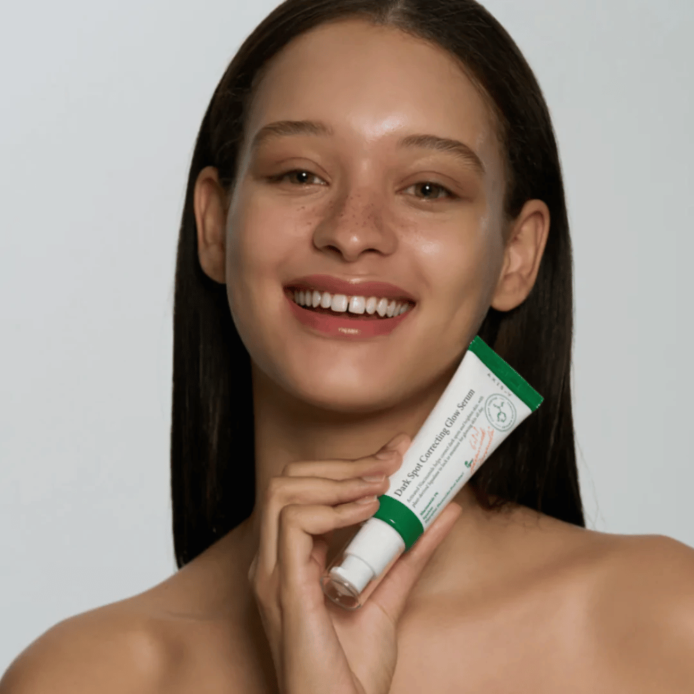 En ung kvinne holder i en tube med AXIS - Y Dark Spot Correcting Glow Serum 50ml.