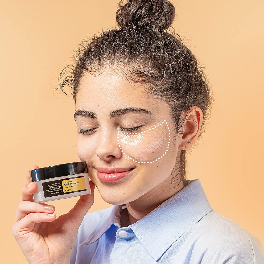 En kvinne som holder en krukke COSRX Advanced Snail Hydrogel Eye Patch 60 stk ansiktskrem.