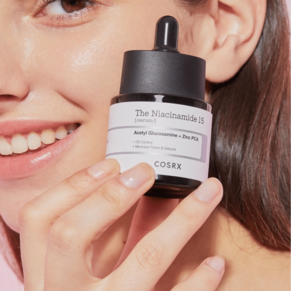 En kvinne holder i en flaske av COSRX Niacinamide 15 Serum 20ml for niacinamid og talgproduksjonen.