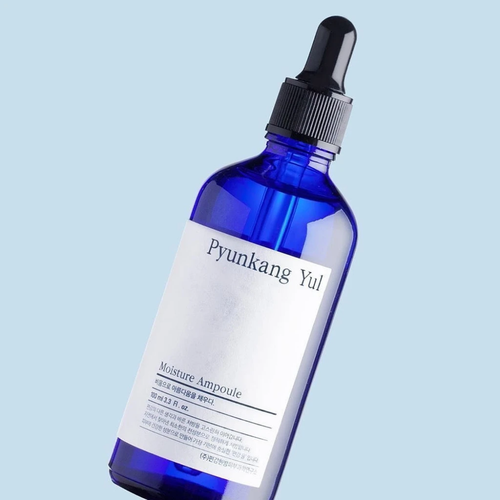 En blå flaske på blå bakgrunn med Pyunkang Yul's Moisture Ampoule 100ml serum.