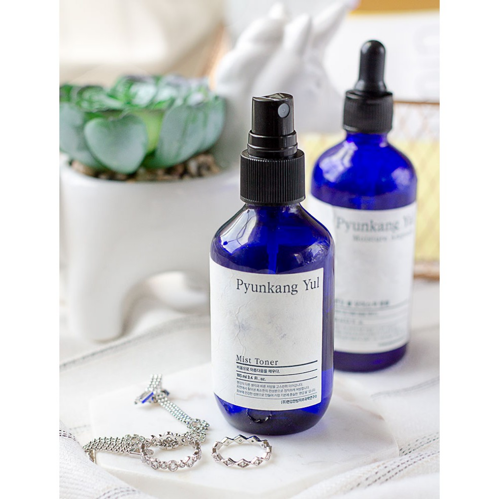 En flaske Pyunkang Yul Mist Toner, en allergivennlig toner, på et bord ved siden av en kaktus.