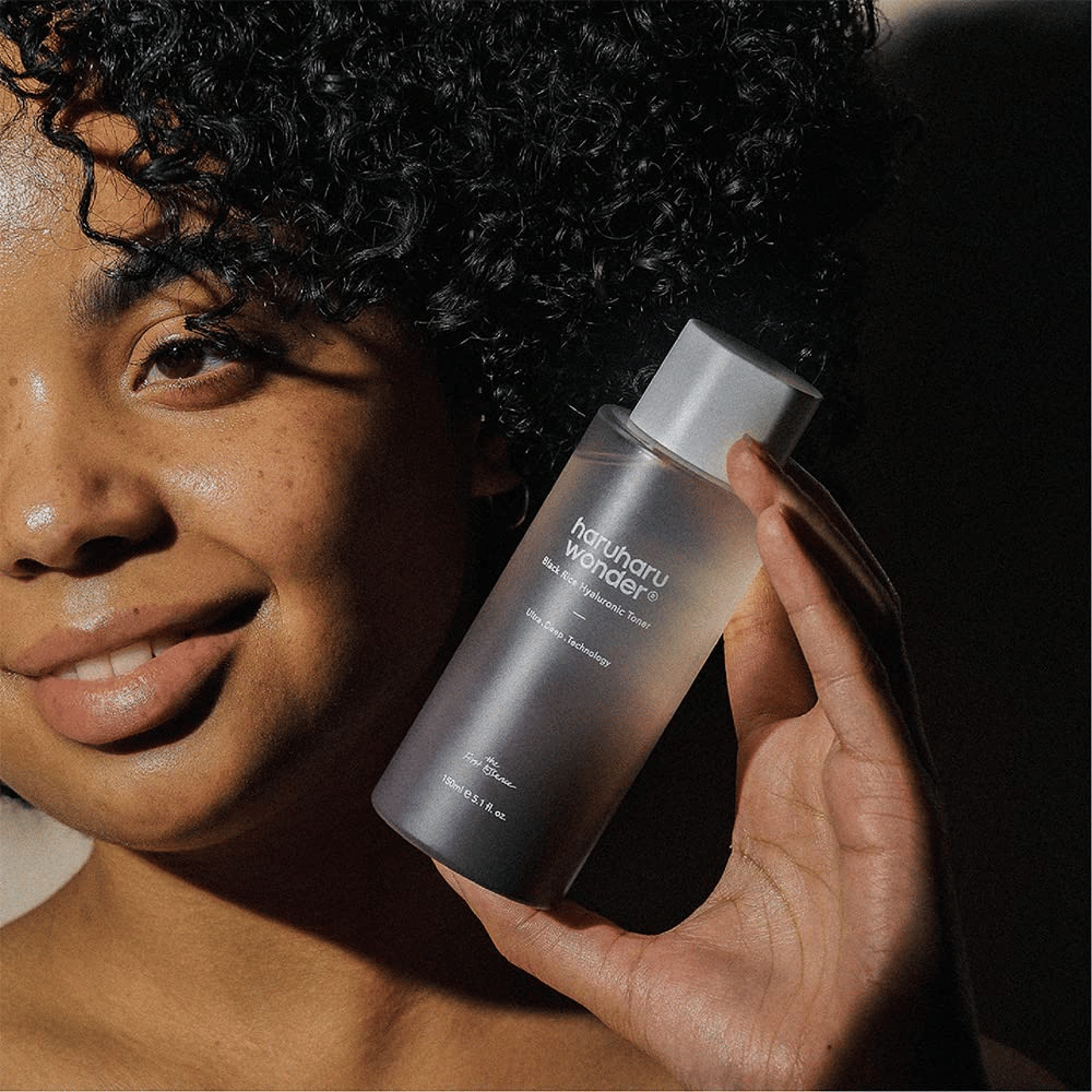 En kvinne som holder opp en flaske Haruharu Wonder Black Rice Hyaluronic Toner Original 150ml.
