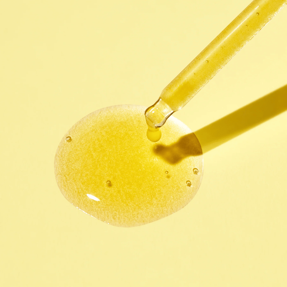 En dråpe væske på en gul bakgrunn, med MISSHAs Vita C Plus Spot Correcting & Firming Ampoule.