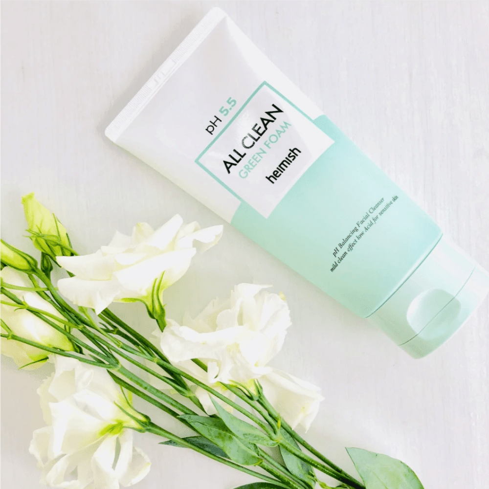 En tube heimish All Clean Green Foam 150ml ved siden av hvite blomster.